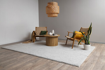 Interior of light living room with soft carpet, armchairs and table