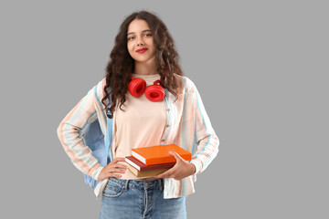 Female student with books on grey background
