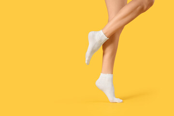 Woman in white socks on yellow background, closeup