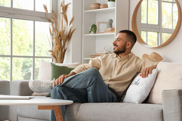 Young man sitting on comfortable sofa at home