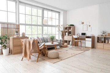 Stylish interior of living room with soft sofa, workplace and armchair