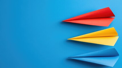 Obraz premium Three colorful paper planes fly against blue background