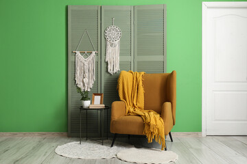 Coffee table, orange armchair and folding screen in interior of beautiful living room