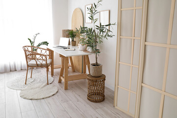Workplace, olive tree, armchair and folding screen in interior of light living room