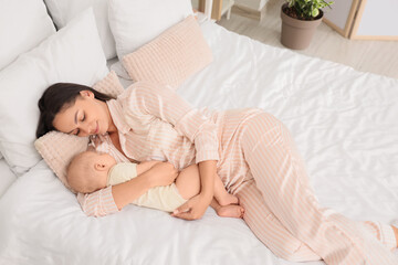 Mother with her sleeping baby lying in bedroom
