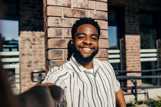 Portrait of smiling black man taking selfies at train station.