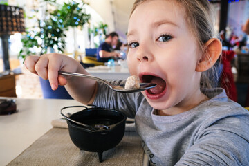 little girl eating dumpling in cafe