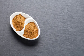 Ground Cinnamon Powder in White Bowl on Slate