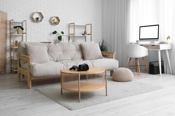 Interior of living room with workplace, sofa and VR glasses on table