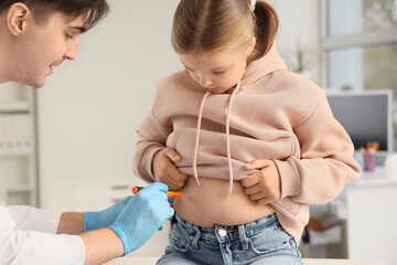 Diabetic girl with doctor using lancet pen in clinic