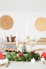 Beautiful festive table setting for Christmas celebration with wreath and candles in dining room
