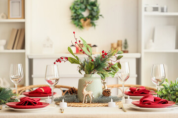 Beautiful festive table setting for Christmas celebration with vase of winter bouquet in dining room