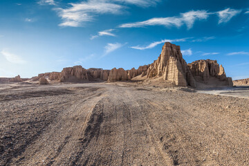 Desert road and Yardang landform mountain natural landscape under blue sky. Road trip in no man's land.