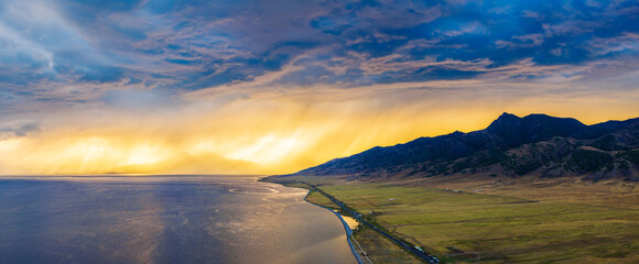 Beautiful Sayram Lake natural landscape at sunset in Xinjiang. Lake and grassland with spectacular sky clouds scenery. Famous travel destination in China.