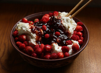Delicious red fresh strawberries with cottage cheese in a clay plate on a wooden table.