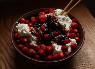 Delicious red fresh strawberries with cottage cheese in a clay plate on a wooden table.