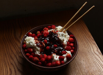 Delicious red fresh strawberries with cottage cheese in a clay plate on a wooden table.