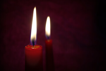 Red candles with flickering flame against a textured dark background