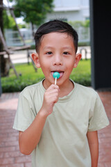 Asian boy kid eating lollipop candy while stay in the garden.