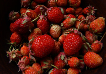 Delicious red fresh strawberries in a clay plate on a wooden table.