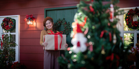 Gift Bearer Holding Christmas Present by Decorated House for Festive Giving