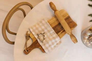 Wooden rolling pin sits on a table next to a cookie cutter