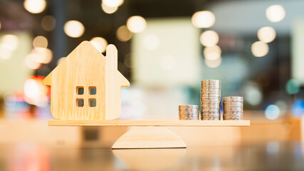 Wood house and Coins stack with balance scale. Money management, financial plan, time value of money. Real estate and property agent offer house concepts.