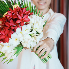 Woman hand wearing a diamond ring and holding flower bouquet. Idea for marriage proposal, romantic surprise, wedding, engagement and valentines day concept