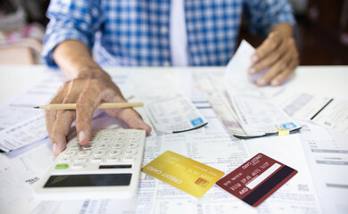 Asian man sitting at desk calculate receipt of expenses and all loan bills and try to find money to pay credit card debt, financial problem and inflation economy concept