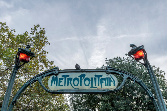 A pigeon perches on a metro sign in Paris, France