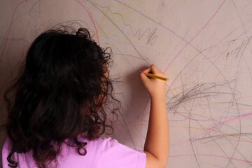 Asian girls are having fun scribbling on the walls using colored pencils.
