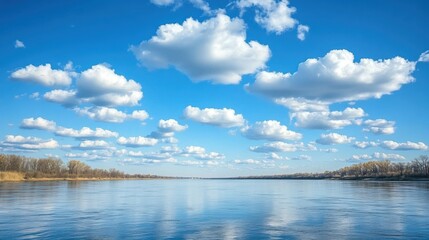 A serene river scene under a blue sky filled with fluffy clouds reflecting on the water's surface, creating a tranquil atmosphere.
