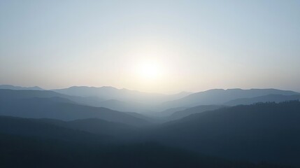 Fototapeta premium A hazy sunrise over a mountain range with a soft, warm glow, creating a peaceful and tranquil atmosphere.