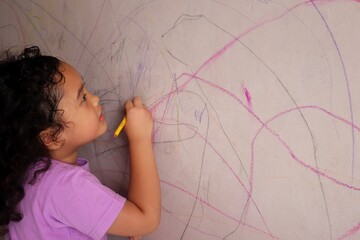 Asian girls are having fun scribbling on the walls using colored pencils.
