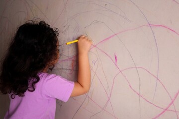 Asian girls are having fun scribbling on the walls using colored pencils.
