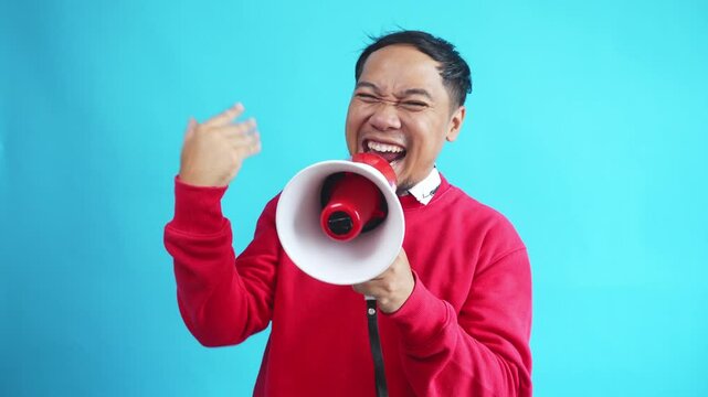 Young Expressive Asian Man Using Megaphone Inviting And Announces Discounts And Sales On Light Blue Background