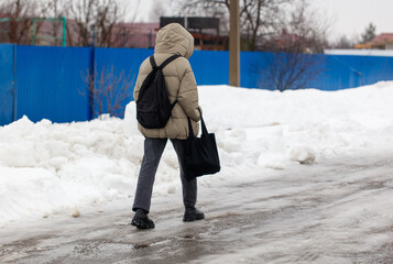 A person wearing a backpack and a coat is walking on a snowy road