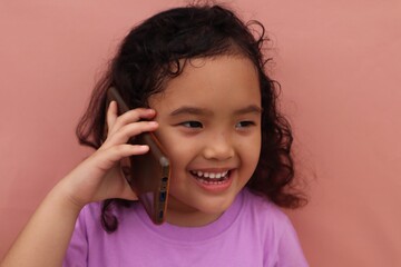 Asian girl is talking on cell phone with adorable face, close up view.

