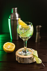 A gin and tonic with lemon and cucumber on a wooden table