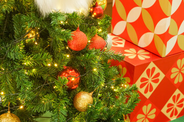 Celebrate the holidays with a Christmas tree with bright lights and festive decorations in December. Next to it is a gift box.