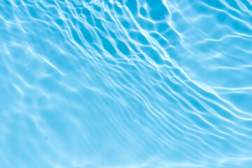 Blue water with ripples on the surface. Defocus blurred transparent blue colored clear calm water surface texture with splashes and bubbles. Water waves with shining pattern texture background.