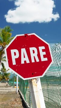 Vertical red stop sign slow motion, tropical beach and coconut palm trees on the background. The end of the road in the journey by latin american countries
