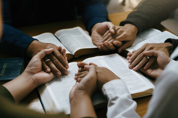 Christian worship and pray. Christian group of people holding hands praying worships together to believe and Bible on a wooden table for devotional for prayer meeting concept.