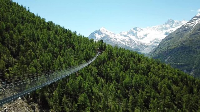 Drone flying away at the Charles Kuonen Suspension Bridge (H&auml;ngebr&uuml;cke), with the snowy mountains at the background in Randa, Wallis, Switzerland.