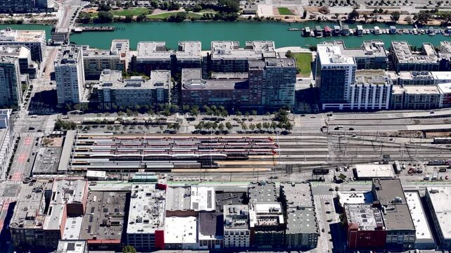 Aerial view of the Caltrain station in San Franciscos Mission Bay area, featuring parked trains, adjacent residential buildings, and the nearby canal.