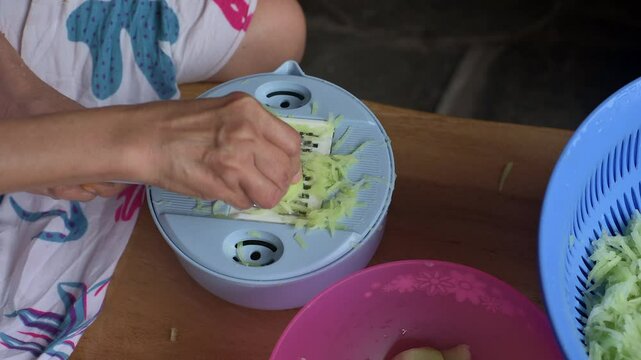 Asian woman close up hand grating some green chayote