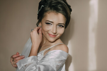 Fototapeta premium A woman in a white dress is smiling and posing for a picture. She is wearing a necklace and earrings