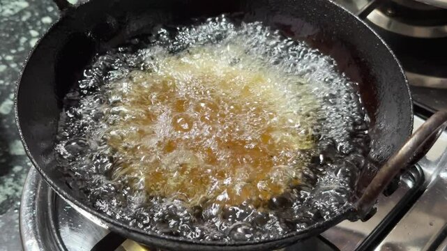 closeup of hand putting puri in the hot oil, Puri or poori is a puffy Indian bread made of wheat flour dough