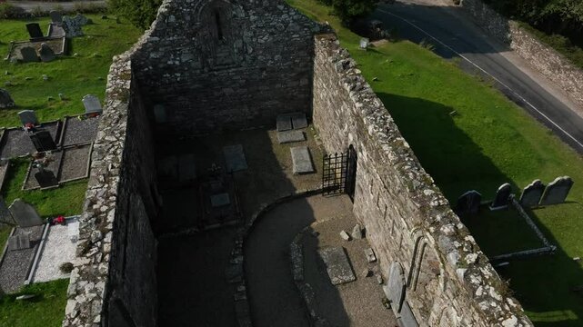St. Declan's Monastery, Ardmore, County Waterford, Ireland, September 2024. Drone high angle orbit slowly pulls back above the interior of the Cathedral ruins in the center of a grassy graveyard.