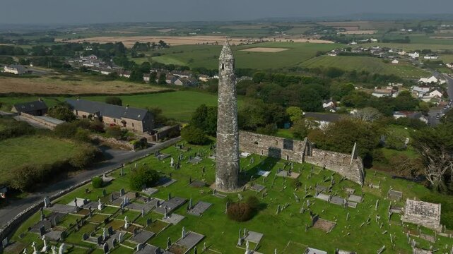 St. Declan's Monastery, Ardmore, County Waterford, Ireland, September 2024. Drone orbits counter clockwise pushing closer to the graveyard with iconic 12th century Round Tower and Cathedral ruins.